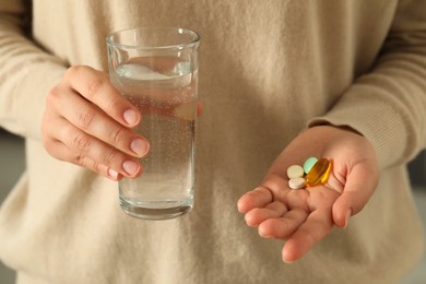 Photo of Young woman with glass of water and dietary supplement pills, closeup