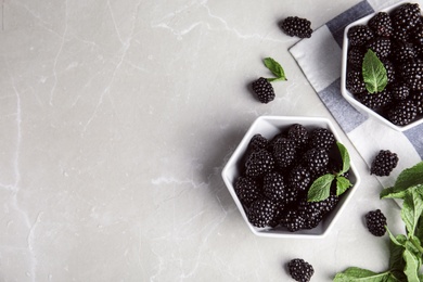 Flat lay composition with tasty blackberries and space for text on grey marble table