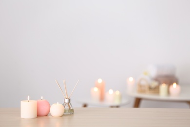 Photo of Candles and reed air freshener on table against blurred background, space for text. Spa concept