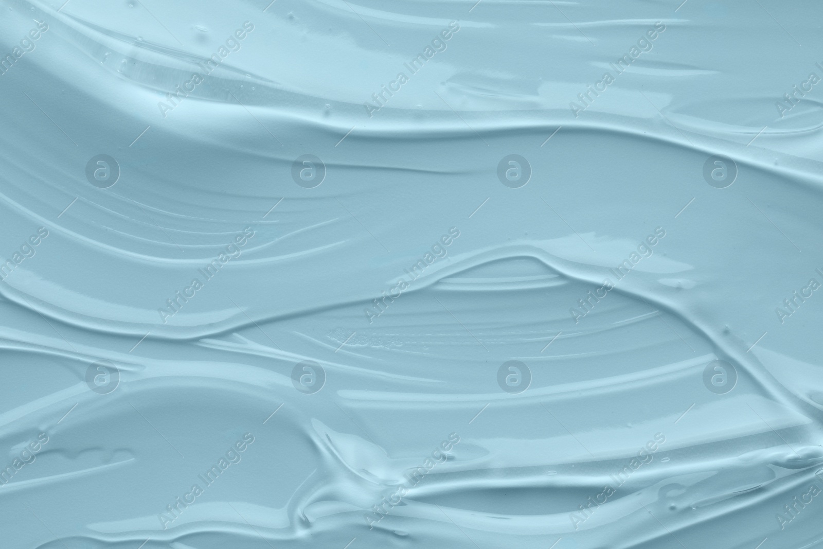 Photo of Clear cosmetic gel on light blue background, top view