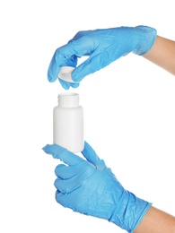 Doctor in medical gloves opening bottle with pills on white background