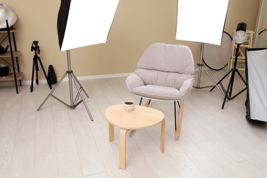 Photo of Interior of modern photo studio with rocking chair, table and professional equipment