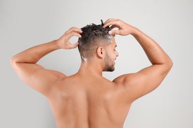 Photo of Young man washing hair on white background, back view