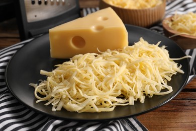 Photo of Grated and whole piece of cheese on wooden table, closeup