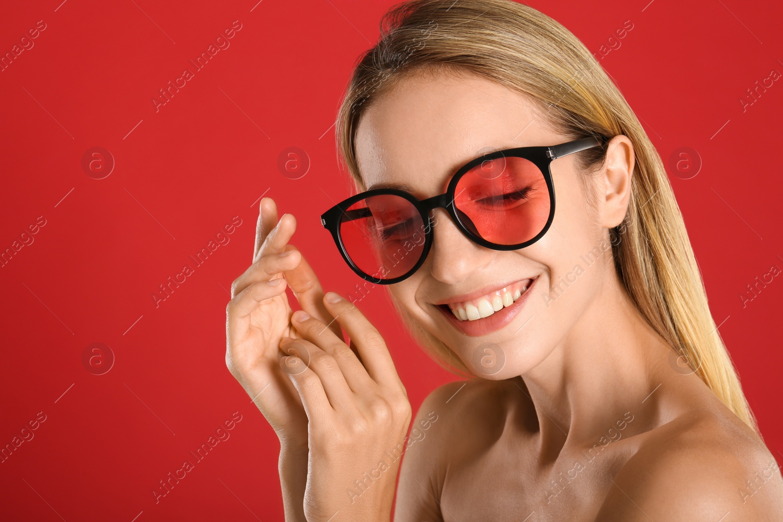 Photo of Beautiful woman in stylish sunglasses on red background