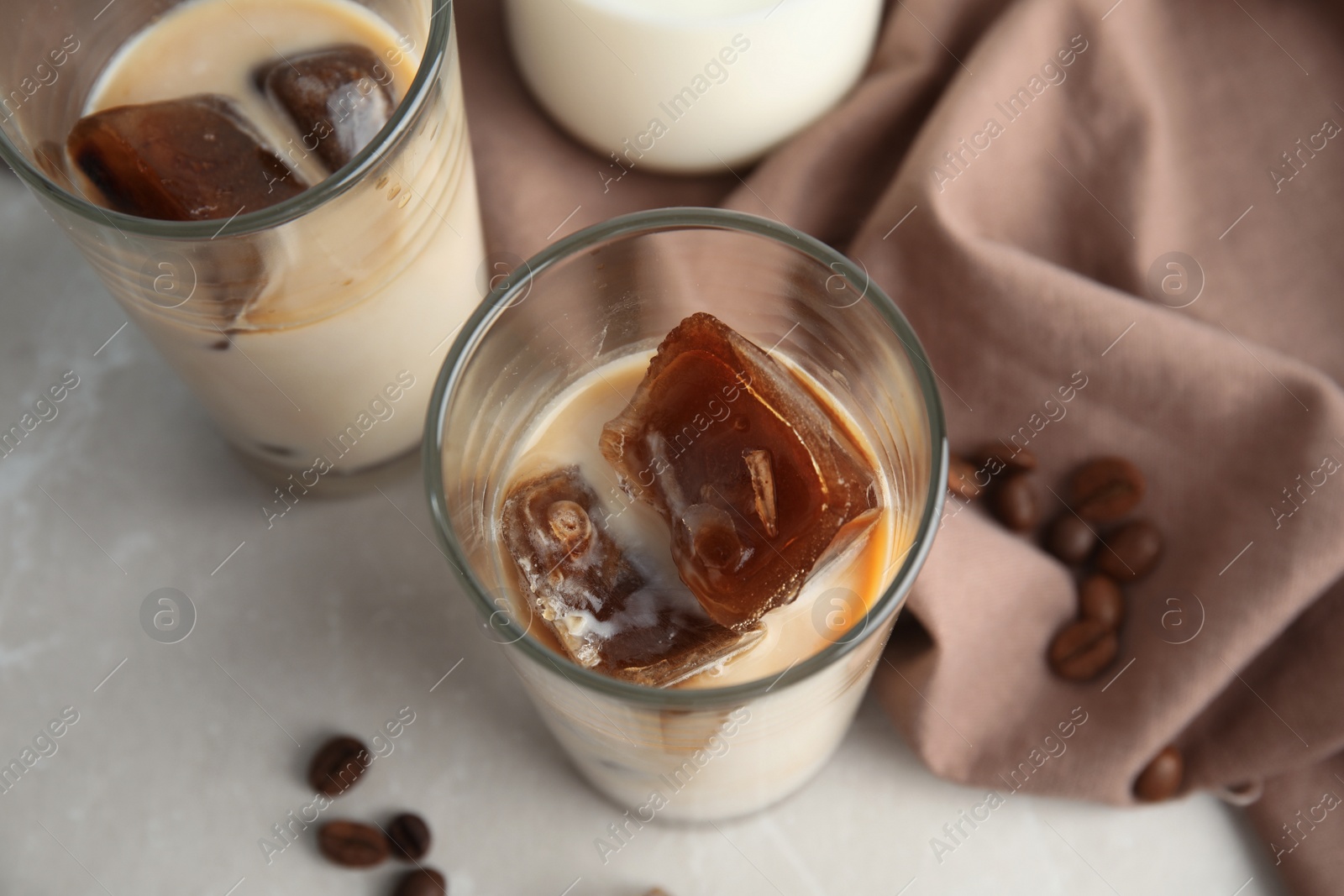 Photo of Glasses of milk with coffee ice cubes on grey background