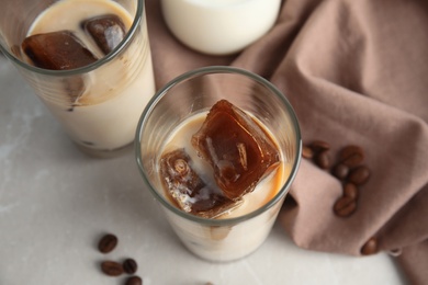 Glasses of milk with coffee ice cubes on grey background