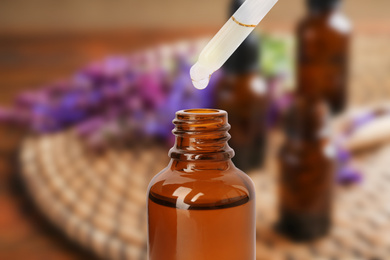 Little bottle with essential oil and dropper against blurred background 