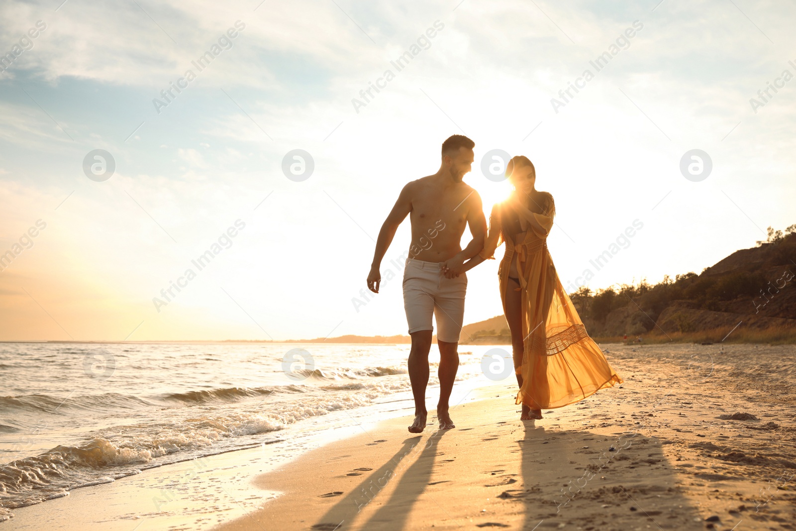 Photo of Happy young couple running together on beach at sunset