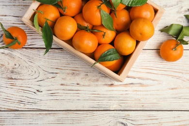 Photo of Crate with fresh ripe tangerines and space for text on wooden background, top view