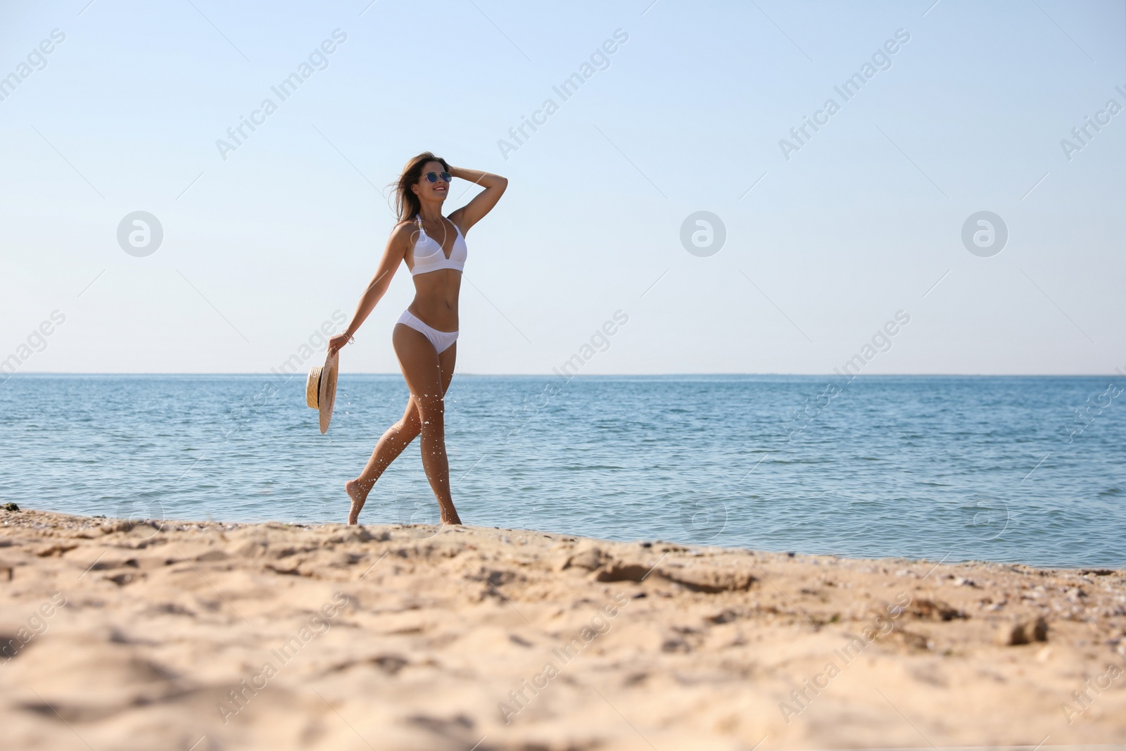 Photo of Young woman with beautiful body on sandy beach. Space for text