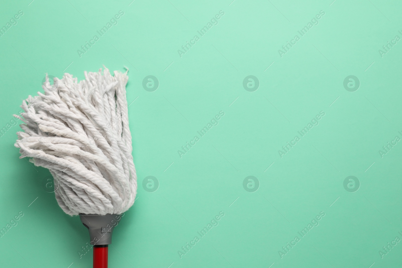 Photo of Mop with plastic handle on turquoise background, top view. Space for text