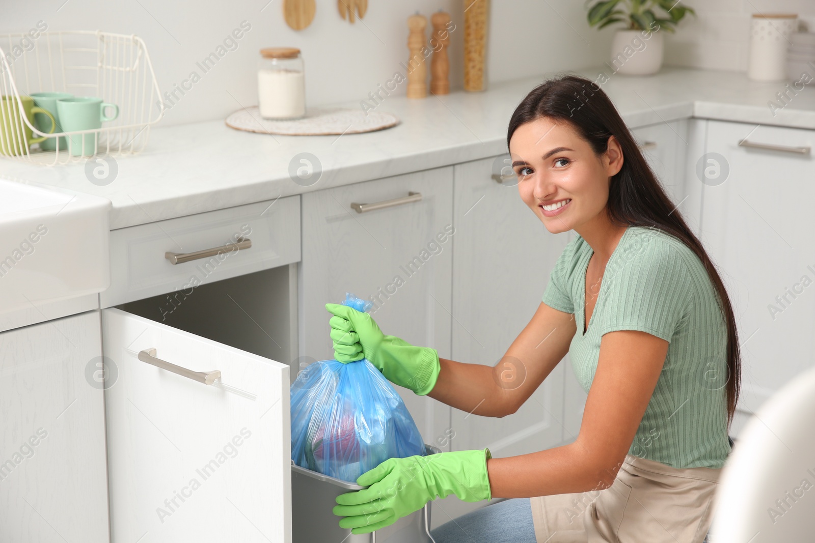 Photo of Woman taking garbage bag out of bin at home