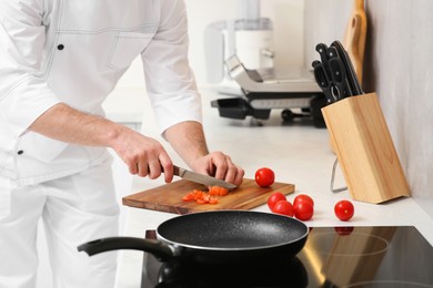 Professional chef cutting tomatoes in kitchen, closeup