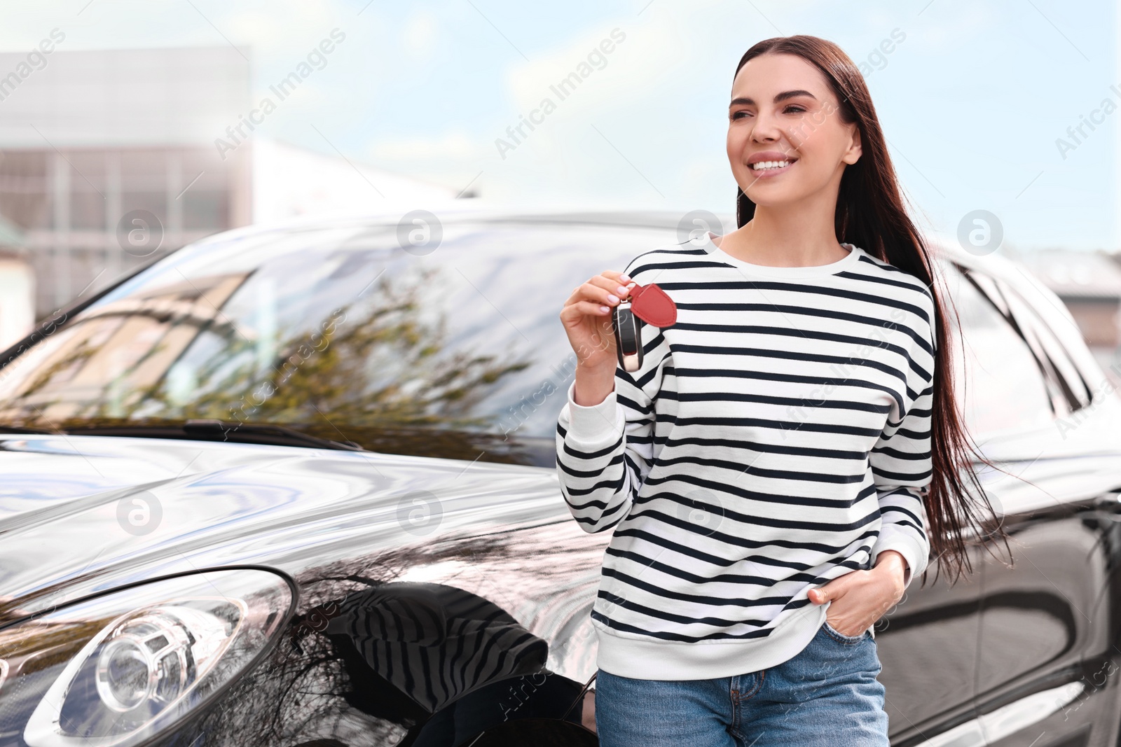 Photo of Woman holding car flip key near her vehicle outdoors