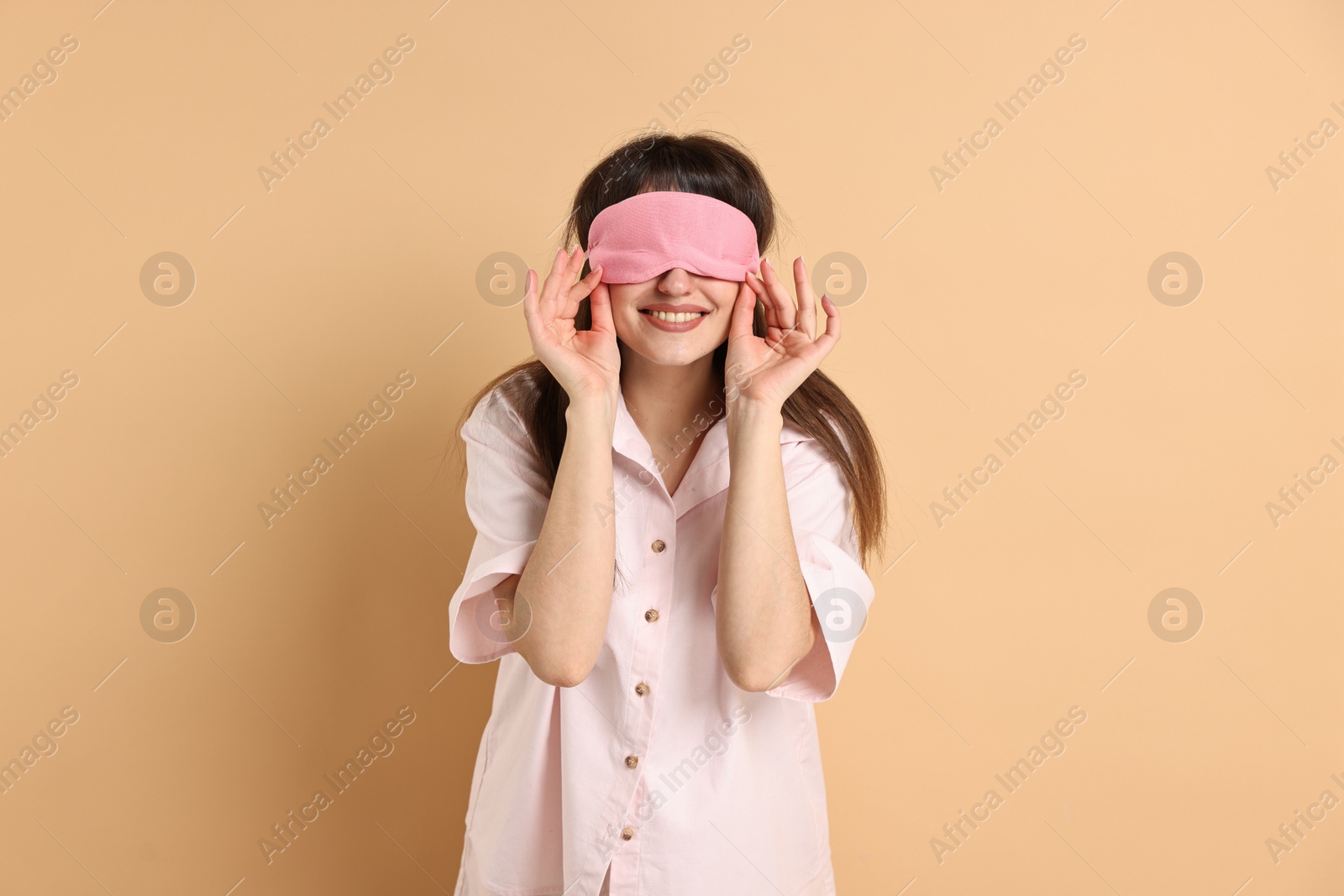 Photo of Woman in pyjama and sleep mask on beige background