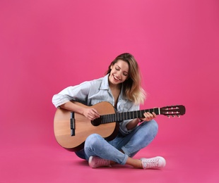 Photo of Young woman playing acoustic guitar on color background