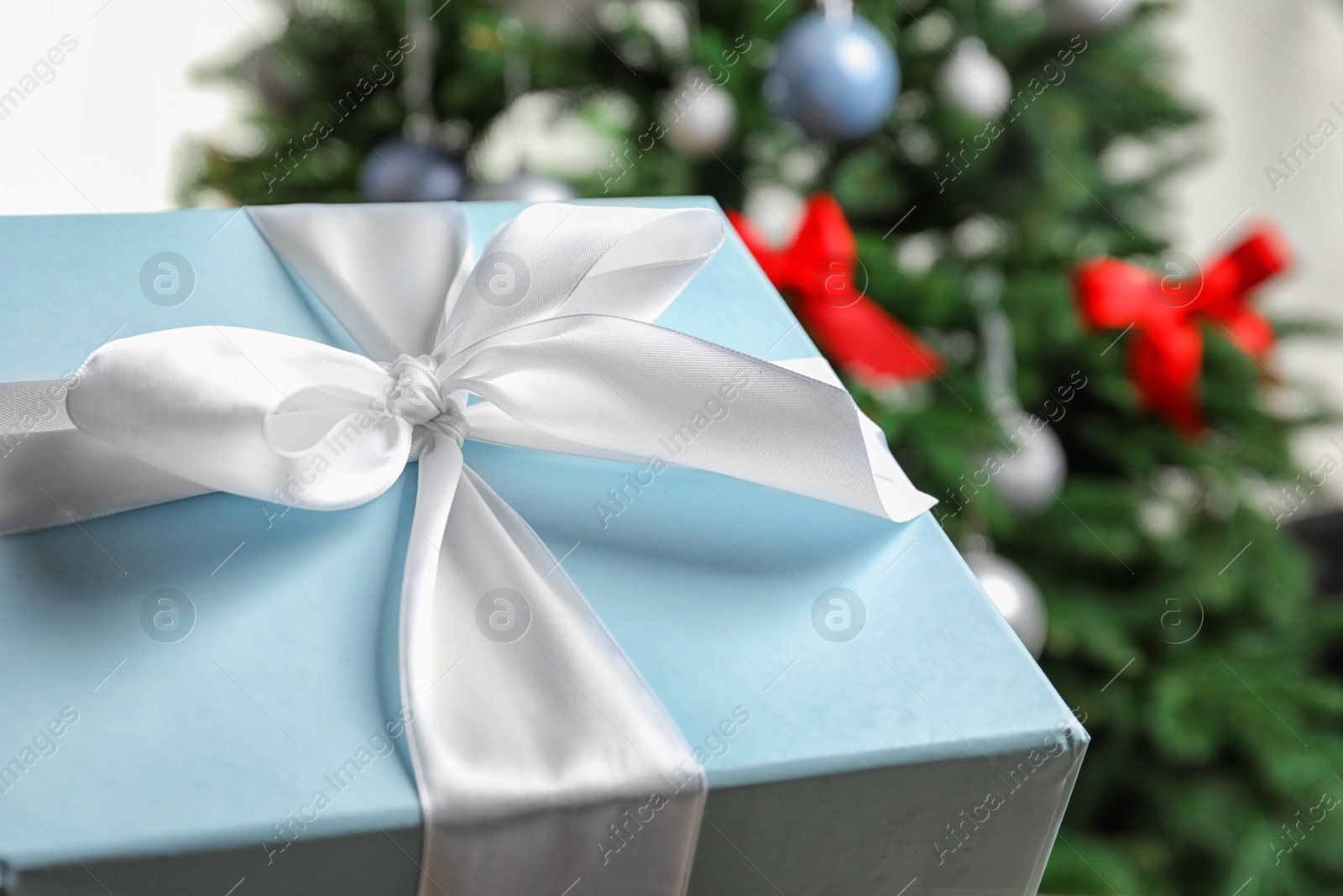 Photo of Beautiful gift box and blurred Christmas tree on background