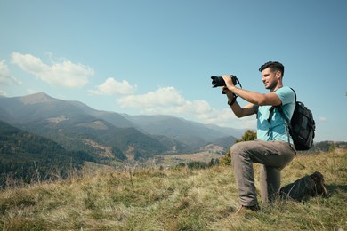 Professional photographer taking picture with modern camera in mountains. Space for text