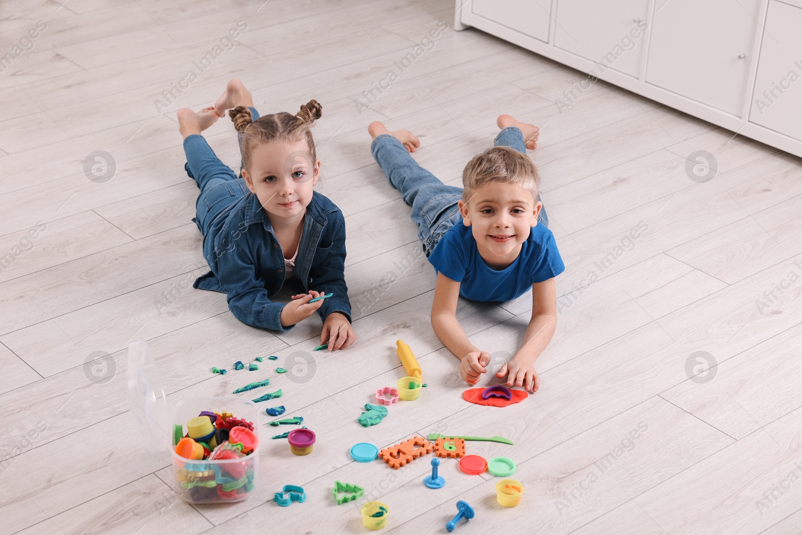 Photo of Cute little children playing on warm floor at home. Heating system