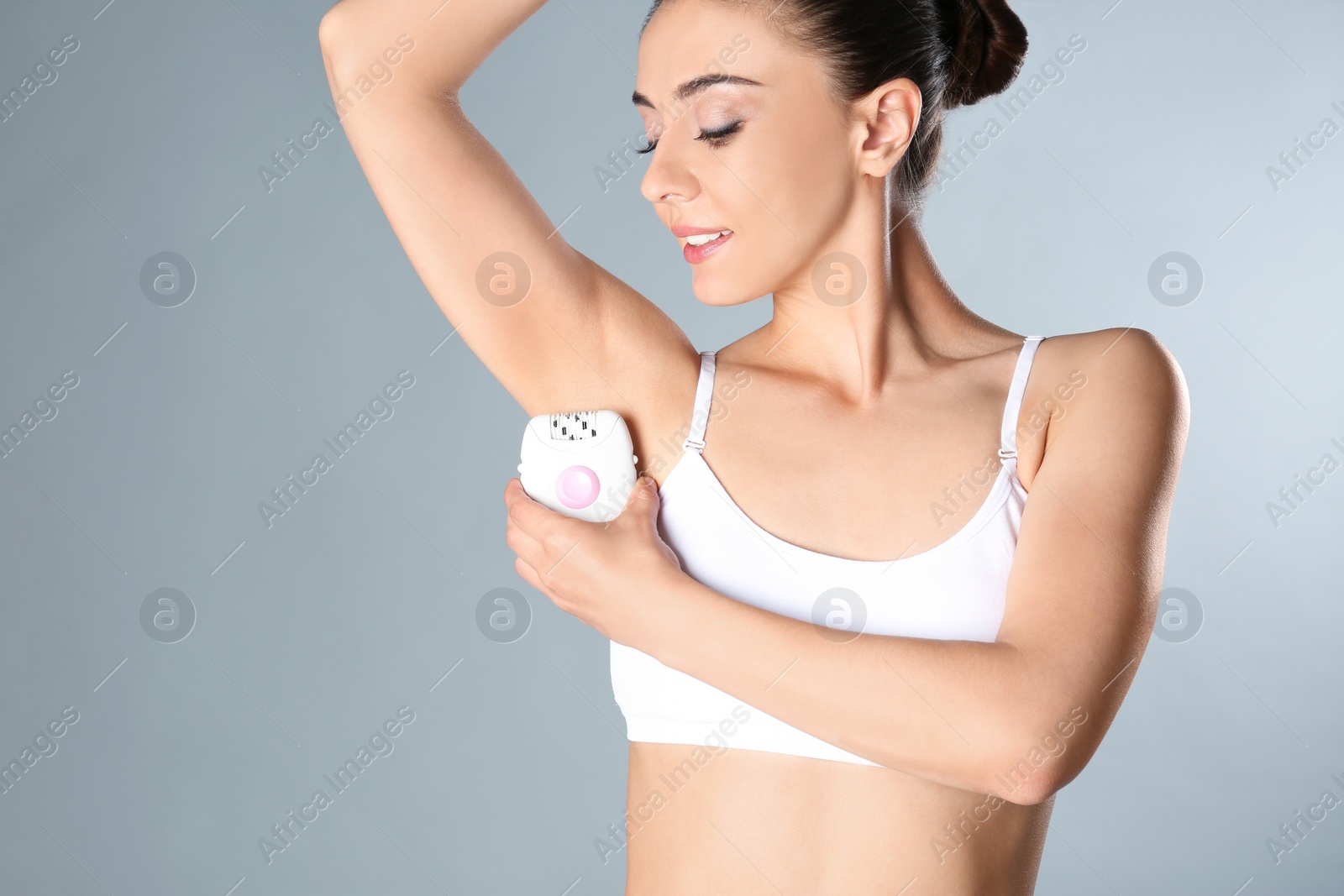 Photo of Woman doing armpit epilation procedure on grey background