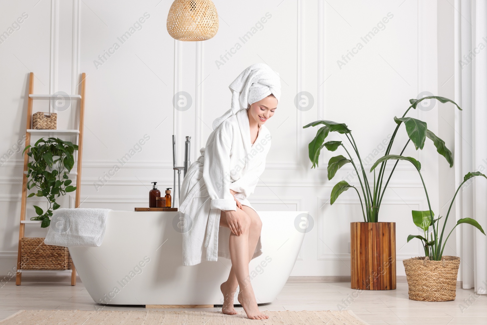 Photo of Beautiful young woman touching her smooth legs in bathroom