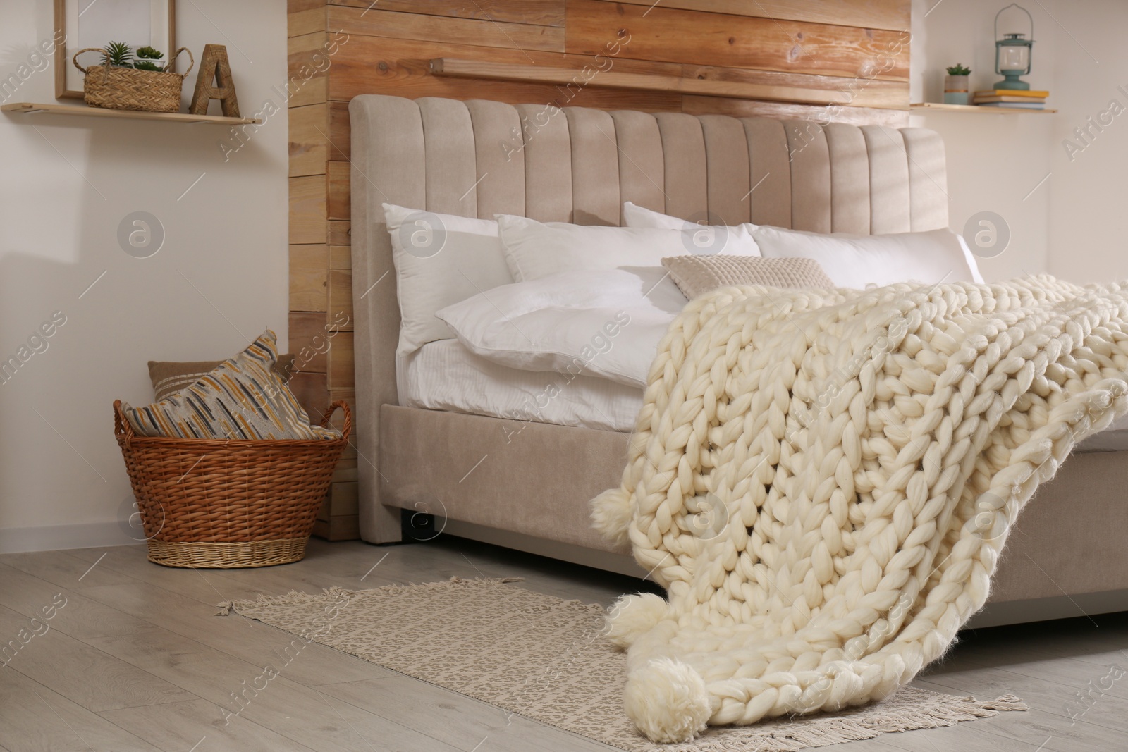Photo of Bed with white knitted plaid in room. Interior design