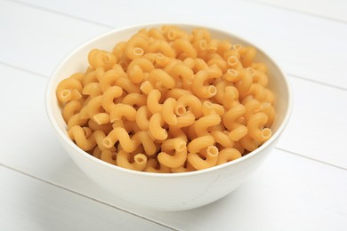 Photo of Raw cavatappi pasta in bowl on white wooden table, closeup