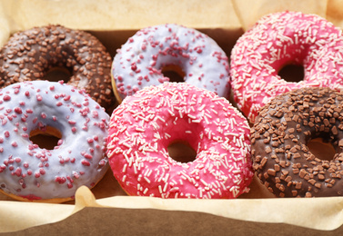 Photo of Delicious glazed donuts on parchment paper, closeup. Sweet pastries