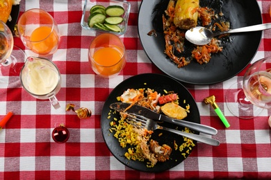 Photo of Flat lay composition of food leftovers after party on table with checkered cloth