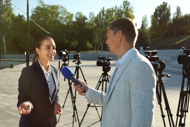Photo of Professional journalist interviewing young woman on city street