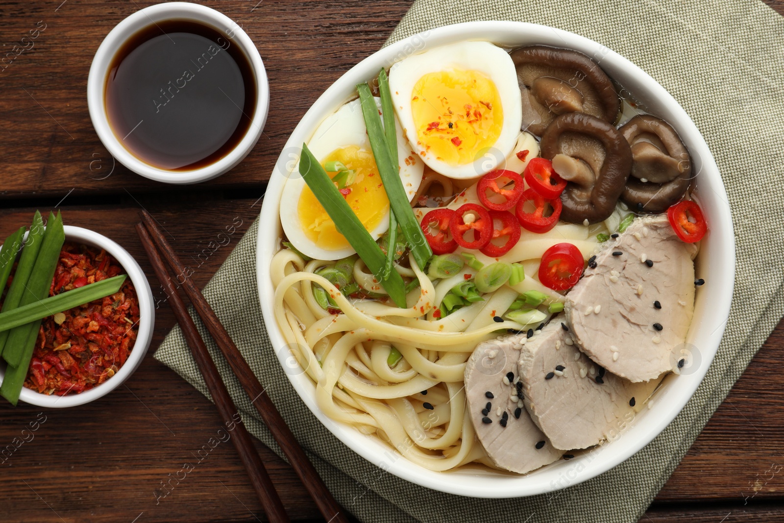 Photo of Delicious ramen with meat in bowl served on wooden table, flat lay. Noodle soup