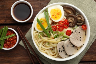 Photo of Delicious ramen with meat in bowl served on wooden table, flat lay. Noodle soup