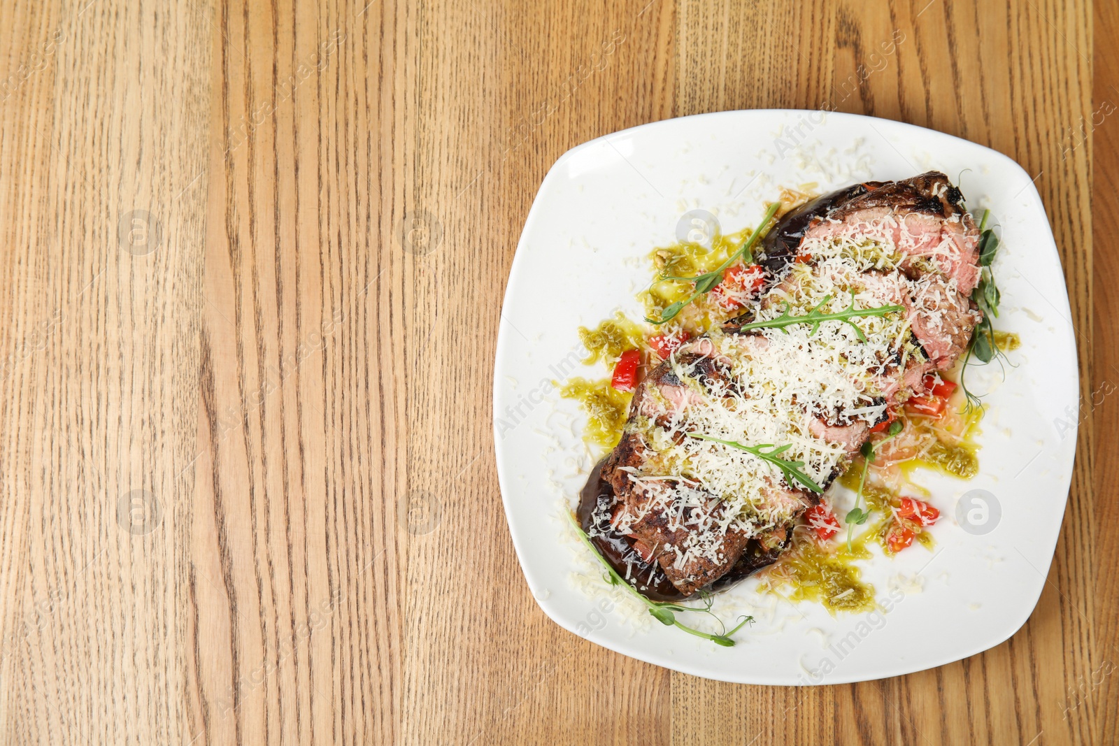 Photo of Delicious roasted meat served on wooden table, top view. Space for text