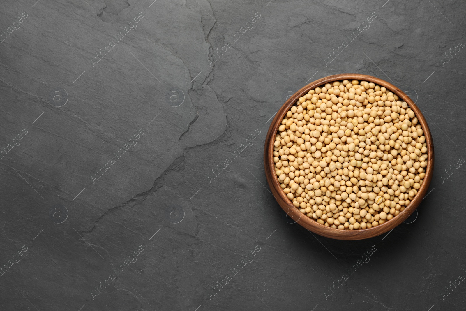 Photo of Soy in bowl on black table, top view. Space for text