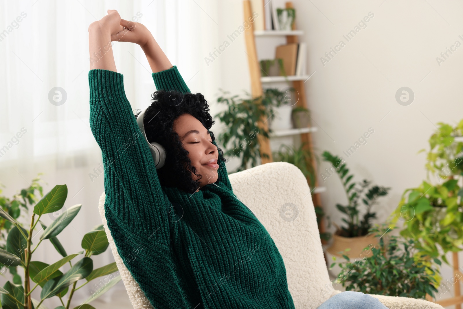 Photo of Woman wearing headphones and listening music in room with beautiful houseplants