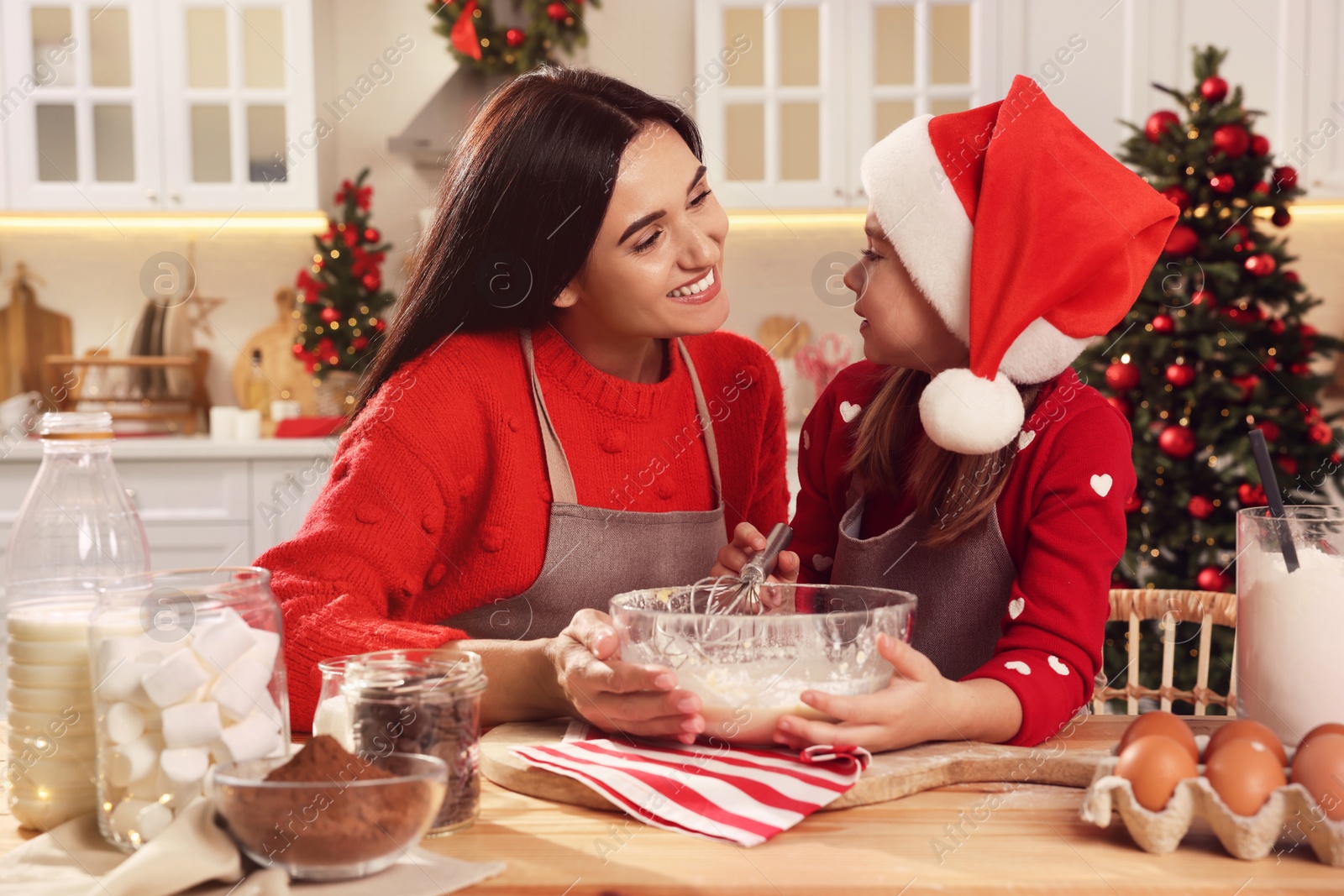 Photo of Happy mother and her daughter making dough for Christmas cookies at home