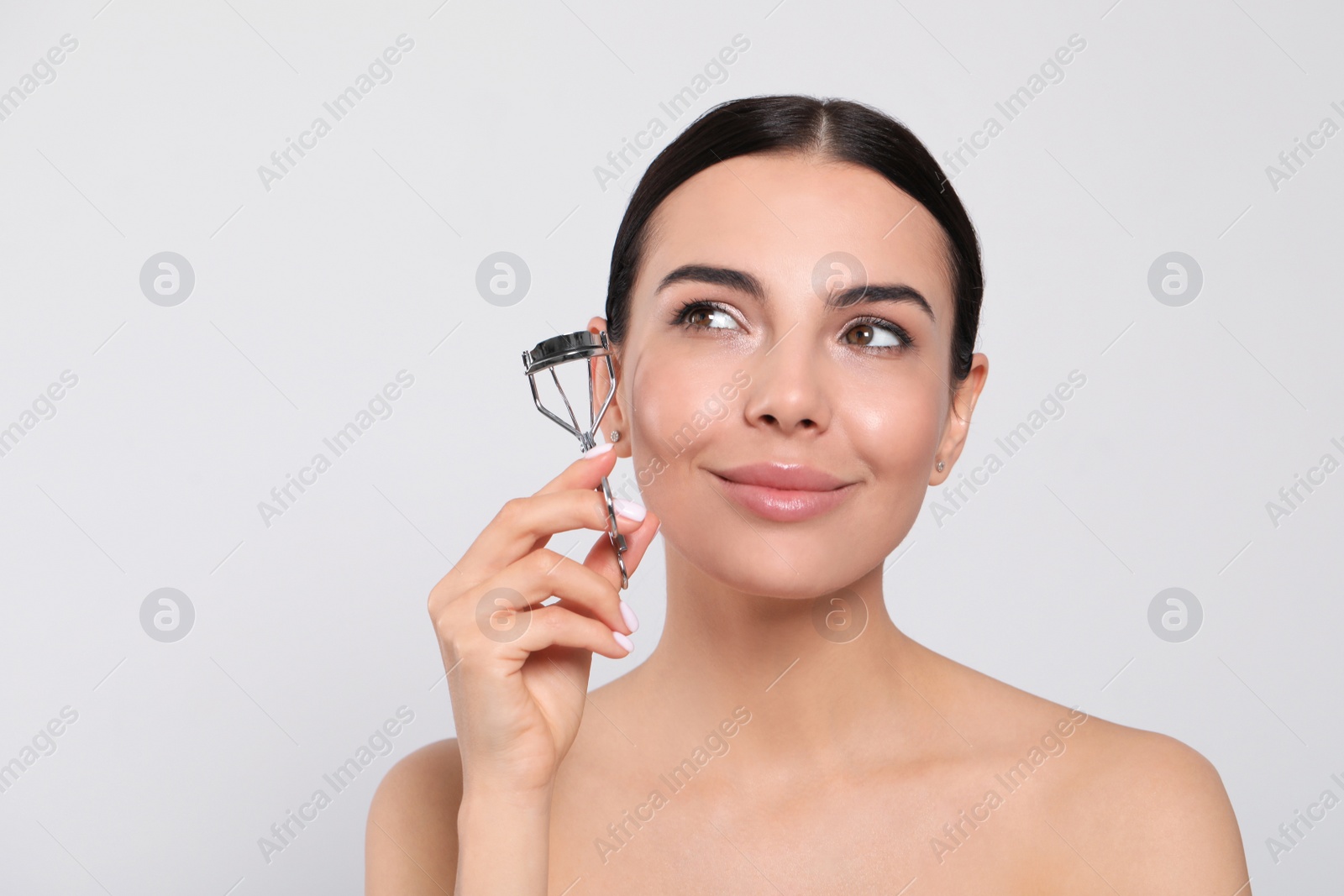 Photo of Beautiful young woman with eyelash curler on white background