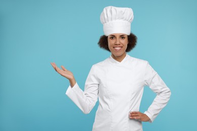 Photo of Portrait of happy female chef in uniform on light blue background