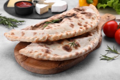Photo of Delicious calzones and products on grey table, closeup