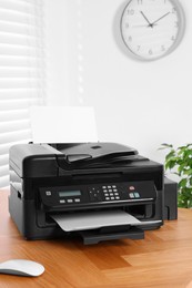 Modern printer with paper on wooden table in home office