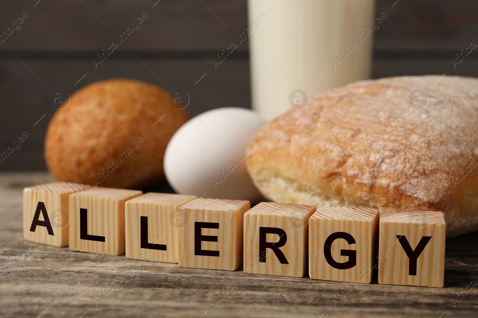 Image of Food allergy. Bread, egg, milk and cubes on wooden table, closeup