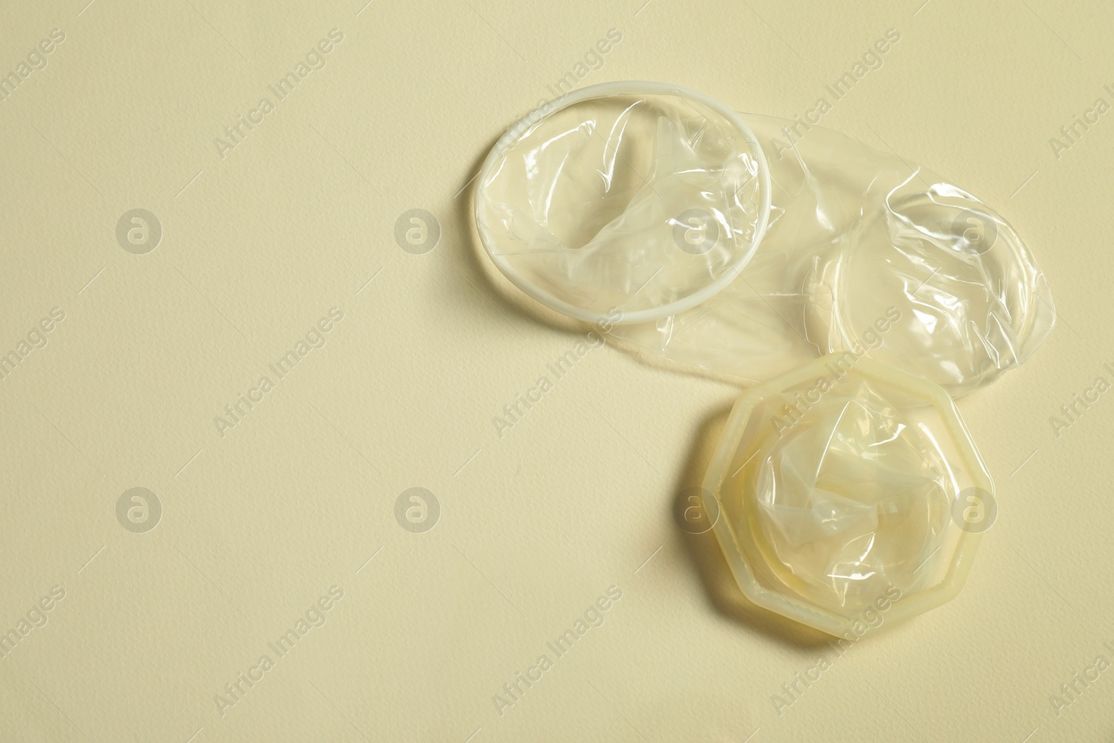 Photo of Female condoms on beige background, above view with space for text. Safe sex