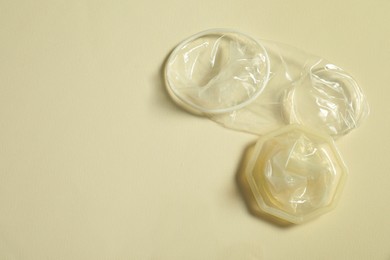 Female condoms on beige background, above view with space for text. Safe sex