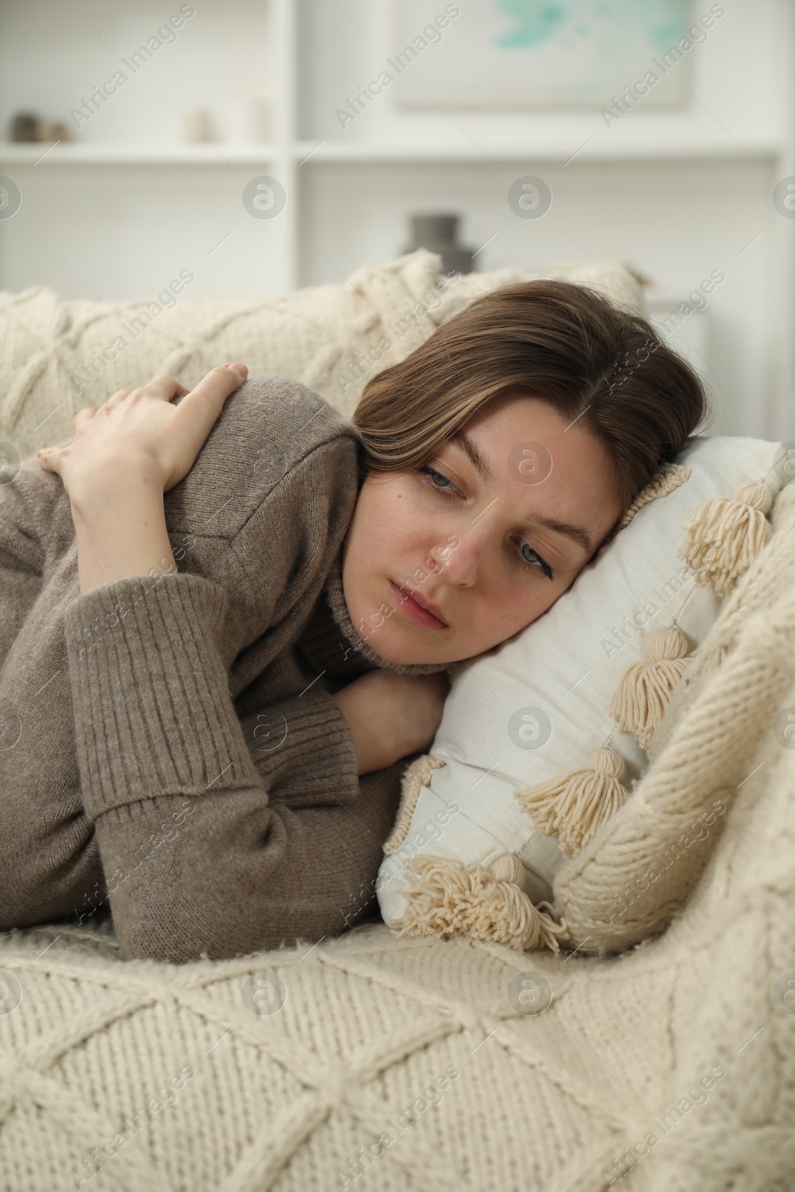 Photo of Sad young woman lying on sofa at home