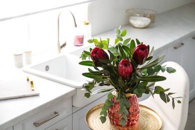 Photo of Bouquet with beautiful protea flowers in kitchen, space for text. Interior design