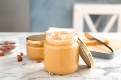 Photo of Jar with creamy peanut butter on table