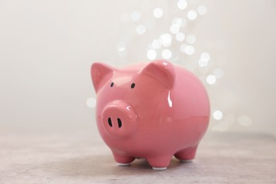 Photo of Piggy bank on grey table against blurred lights