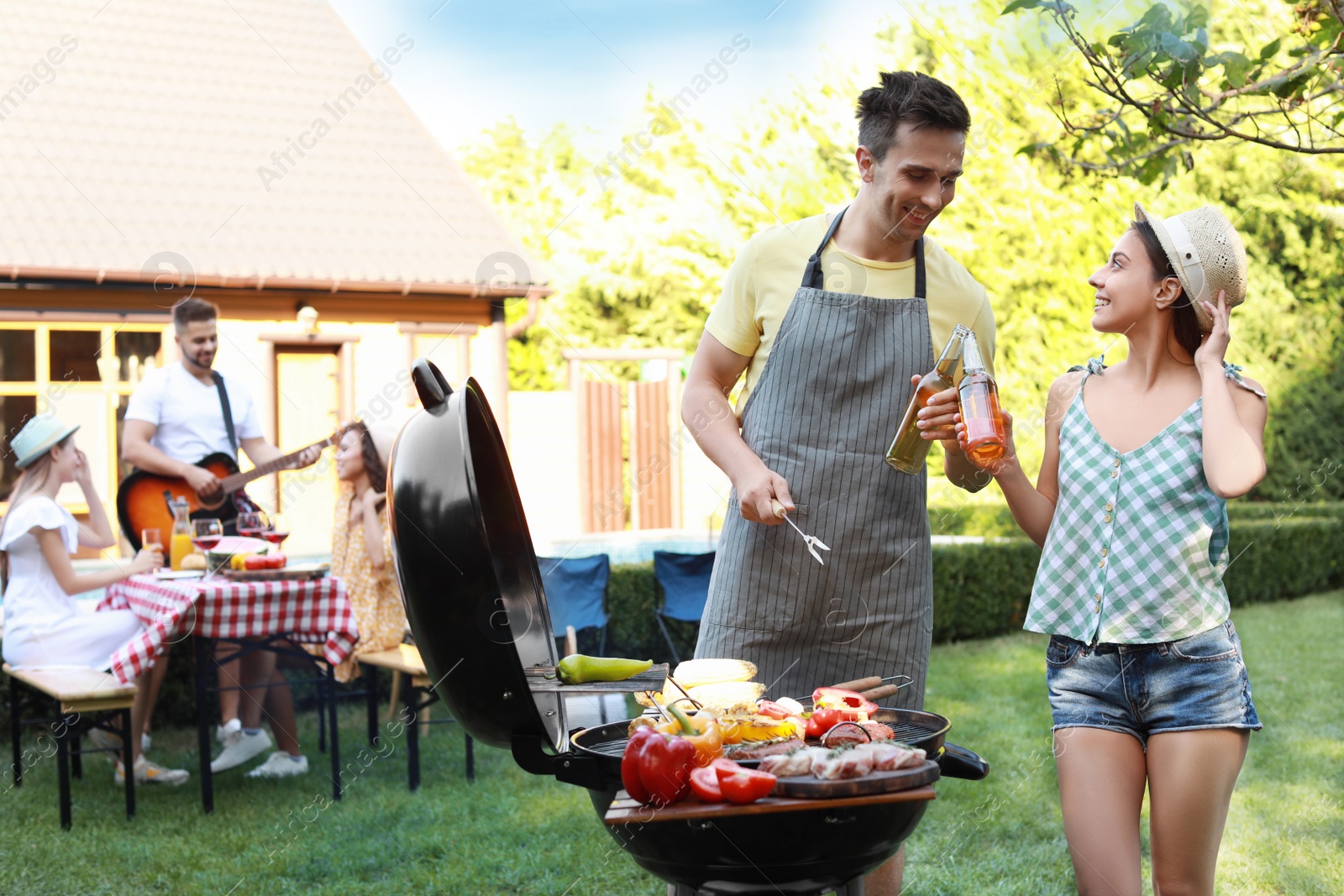 Photo of Young man and woman near barbecue grill outdoors