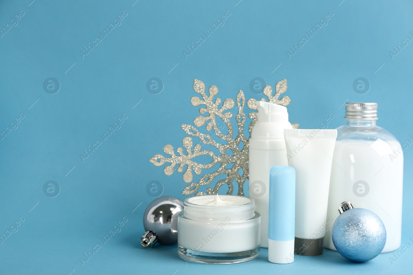 Photo of Beautiful composition with cosmetic products on light blue background, space for text. Winter care